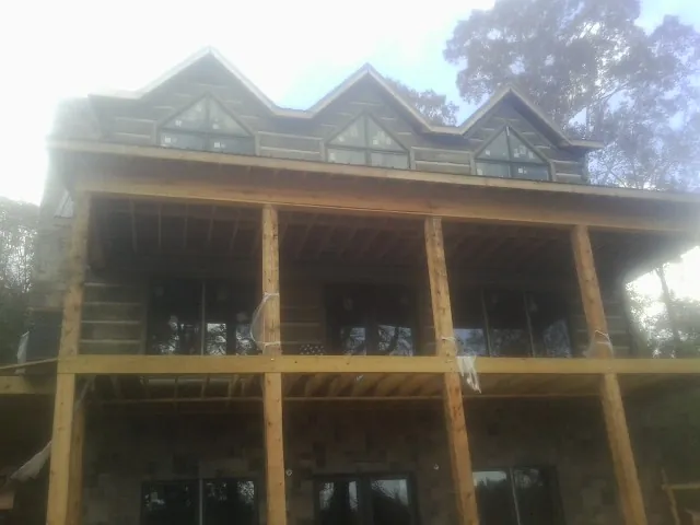 Dormers and porch framing on a large log home under construction — Roof Coating work by our crew in Shawnee