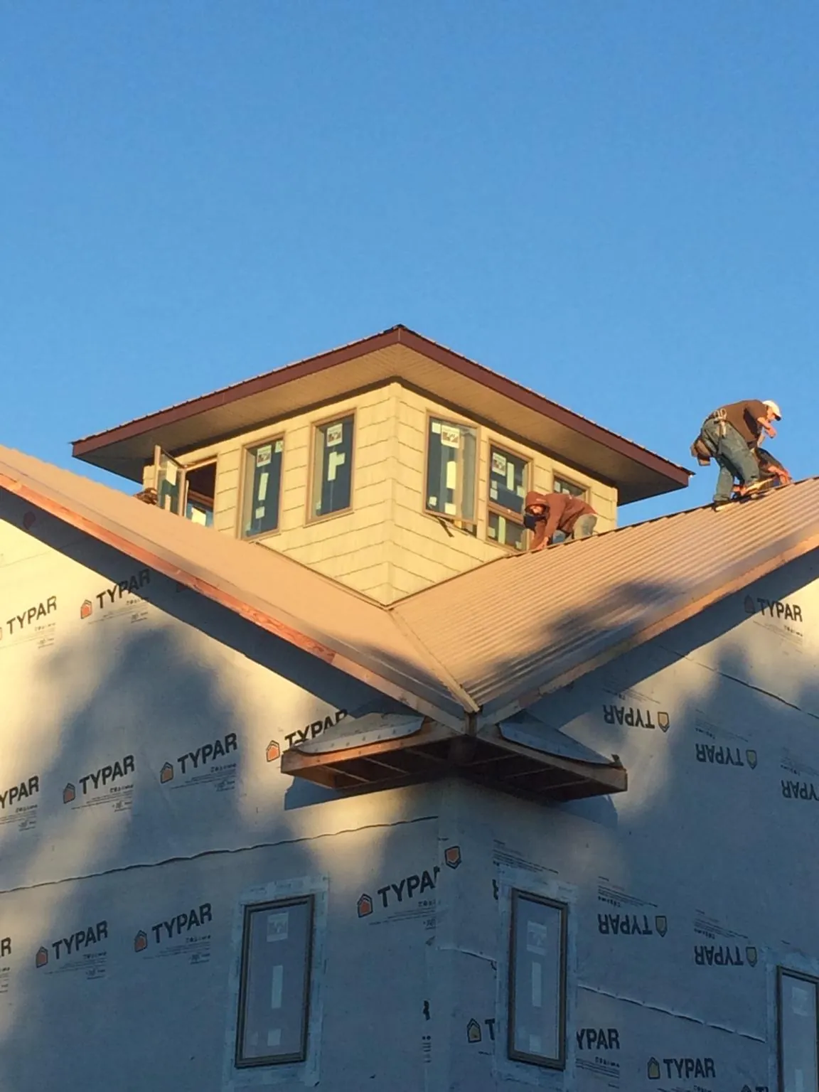 Roofers working around a rooftop cupola on a new metal roof at sunset — Roof Waterproofing in Shawnee by Roofing Brothers
